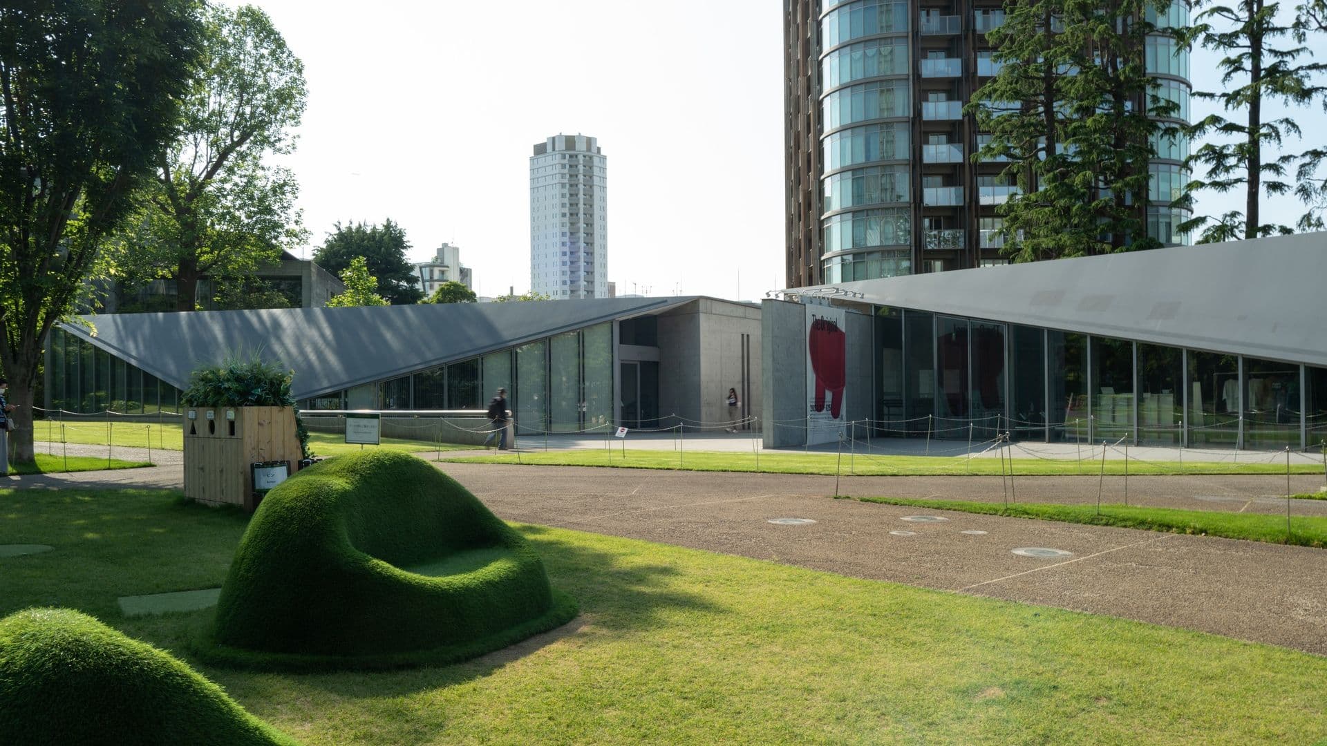 Modern museum building with glass walls and surrounding green lawn and trees in an urban area