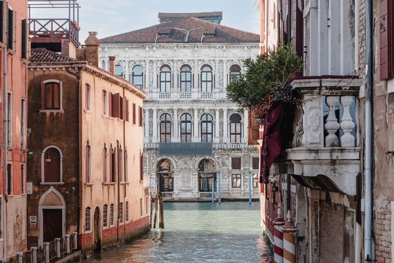 Venetian canal with historic buildings on either side and a grand, ornate building in the background.