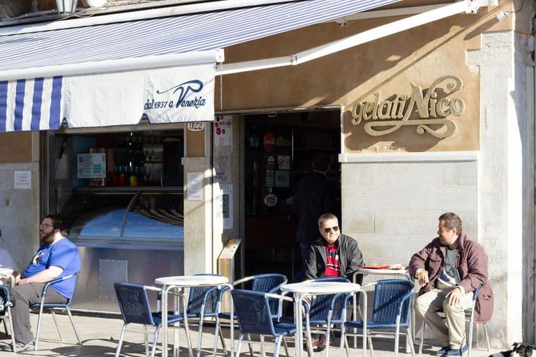 Outdoor seating area of an Italian gelato shop "Gelati Nico" with people sitting at tables.
