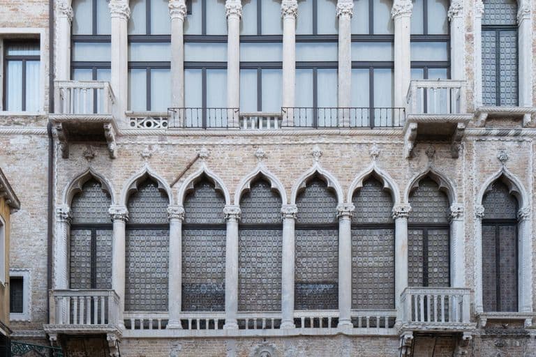 Historical brick building with ornate Gothic windows and small balconies.