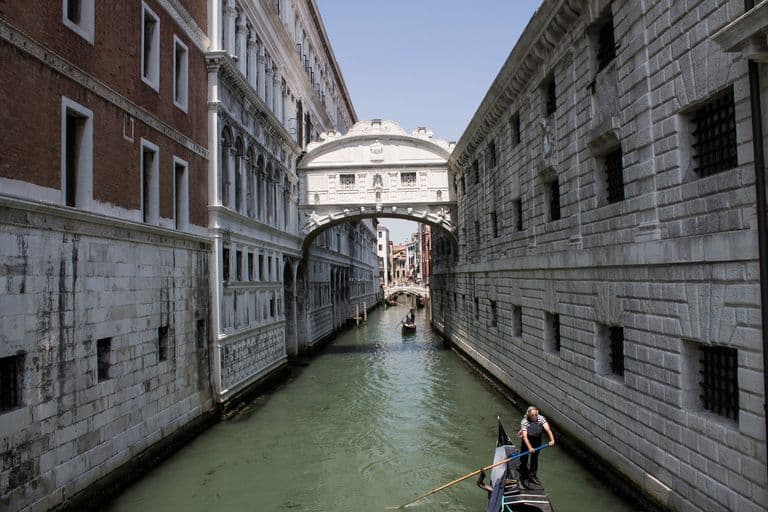Bridge of Sighs in Venice, Italy, spanning a canal with a gondola and gondolier.