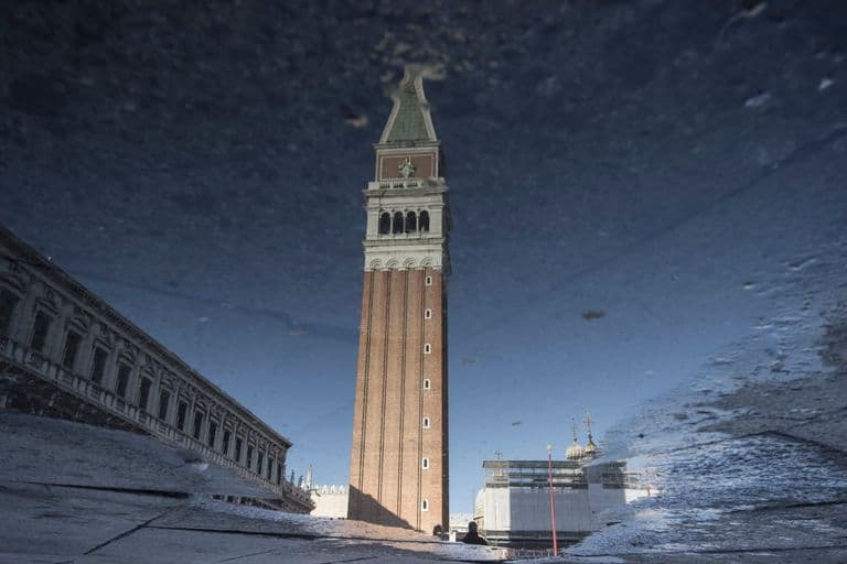 Reflection of St. Mark's Campanile and buildings in a puddle in Venice, Italy.