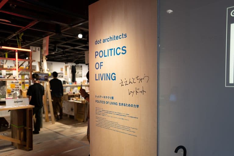 Sign for the 'Politics of Living' exhibition at dot architects, featuring Japanese writing and a part of the exhibition space with people observing displays.