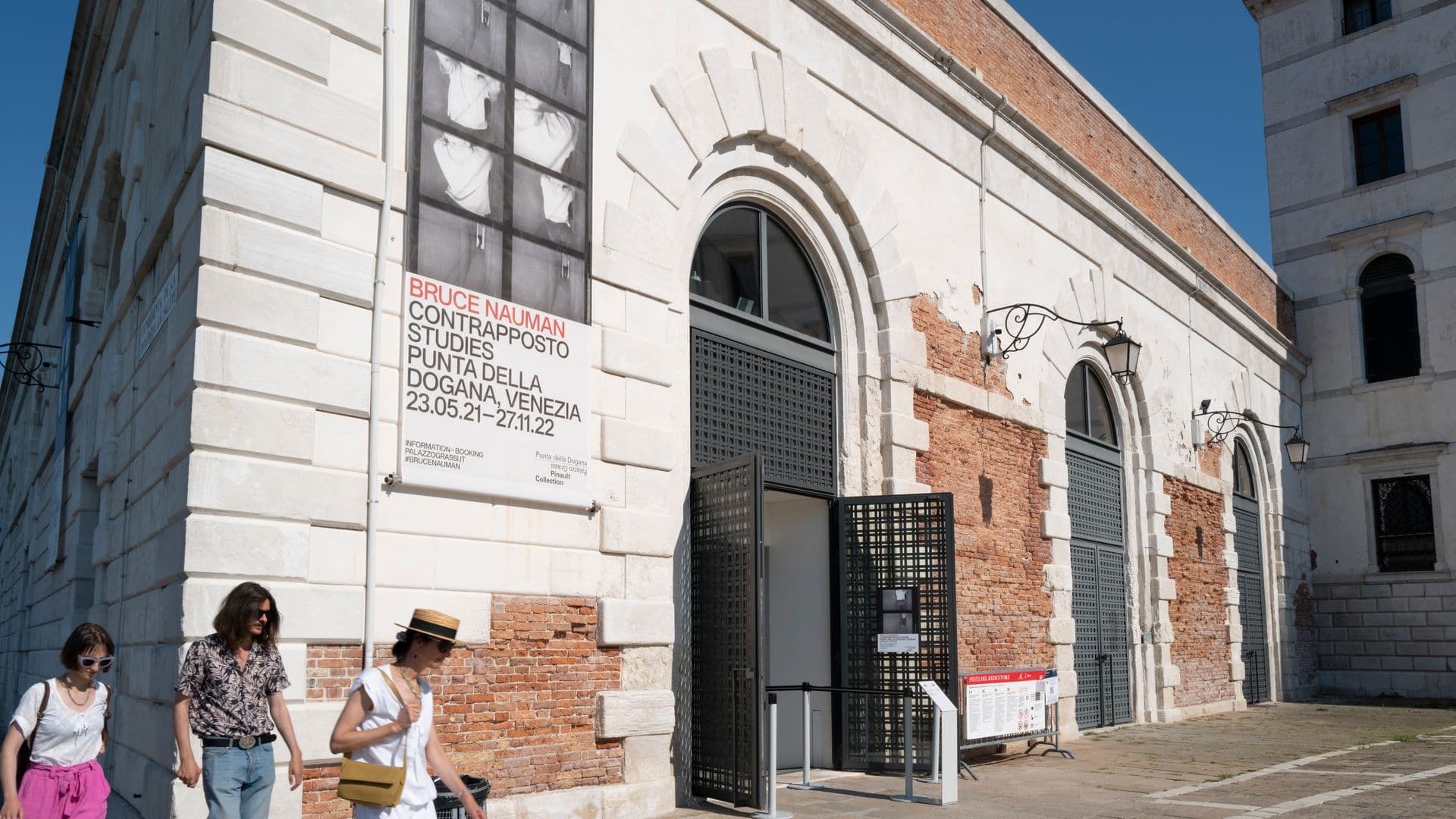 Exterior of Punta della Dogana in Venice with a poster for Bruce Nauman's Contrapposto Studies exhibition.